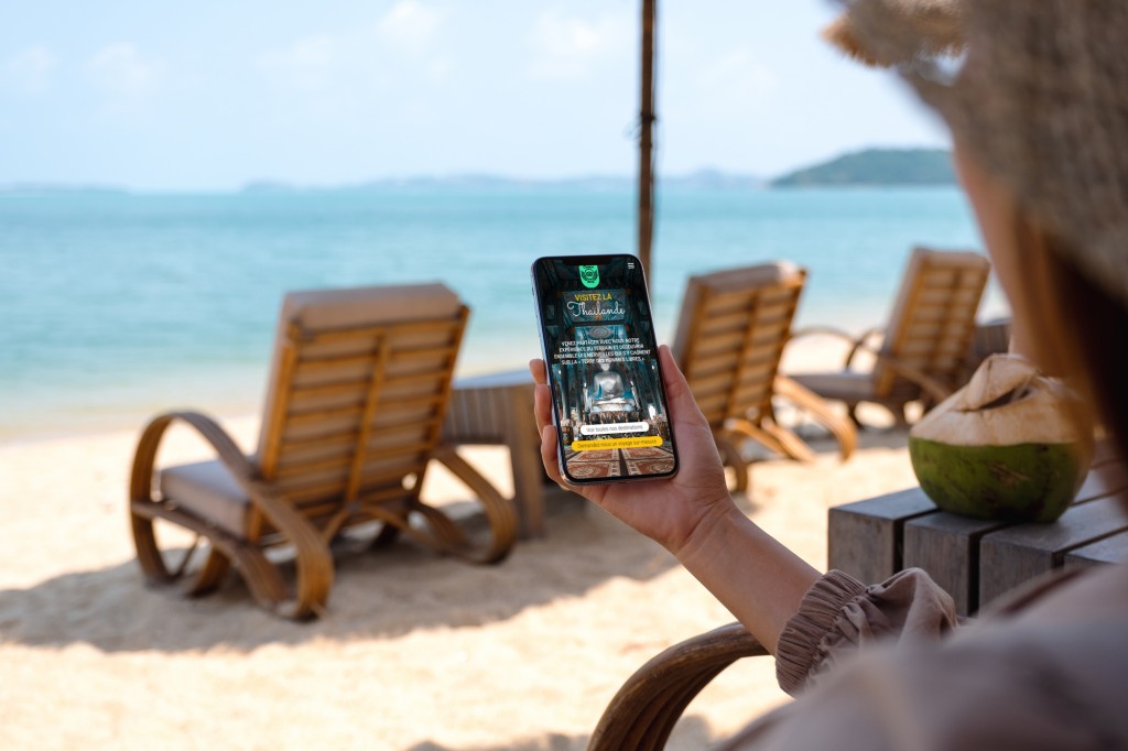mockup-image-woman-holding-mobile-phone-with-blank-desktop-screen-while-sitting-beach